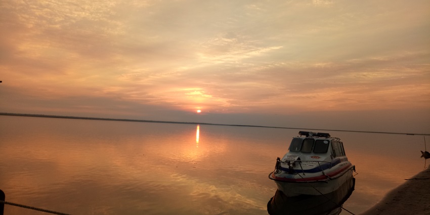 Sunset view at Majuli island, with the sky ablaze in warm hues and the sun dipping.