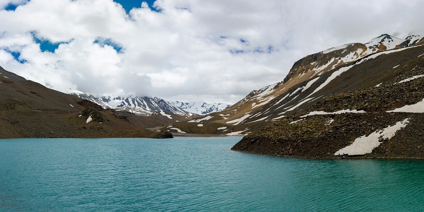 A breathtaking view of a sparkling lake with snow-covered mountains in the background.