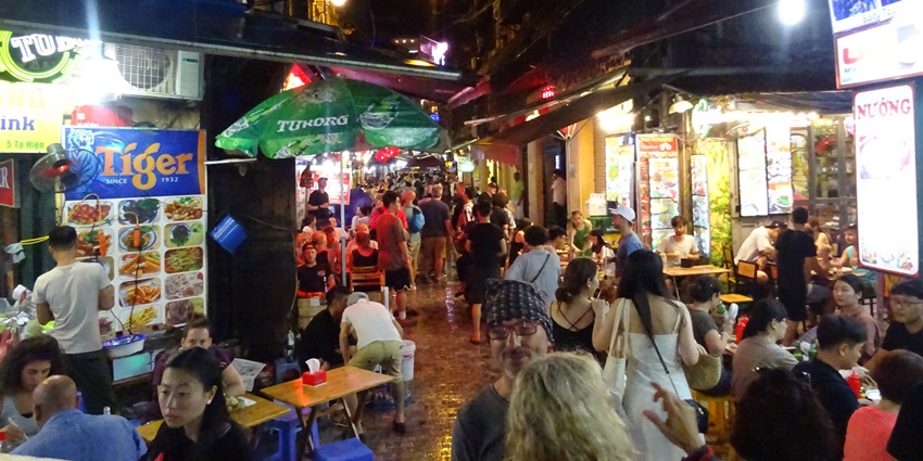 A view of the famous Ta Hien Street decked with people, local stores, and gleaming lights.