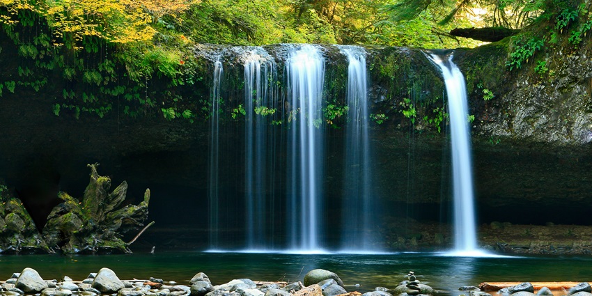 A view of a pool formed at the base of Pampanal Waterfalls surrounded by greenery.