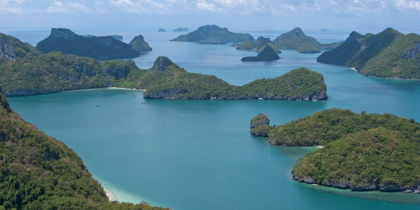 A view of turquoise-blue waters of Talu Island dotted with green-clad peaks in Thailand.