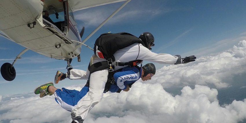 The image of a Tandem jumper taking a leap from a plane above the clouds for diving