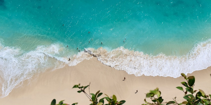 An enchanting view of an azure water body with soft sands on the side during the day.