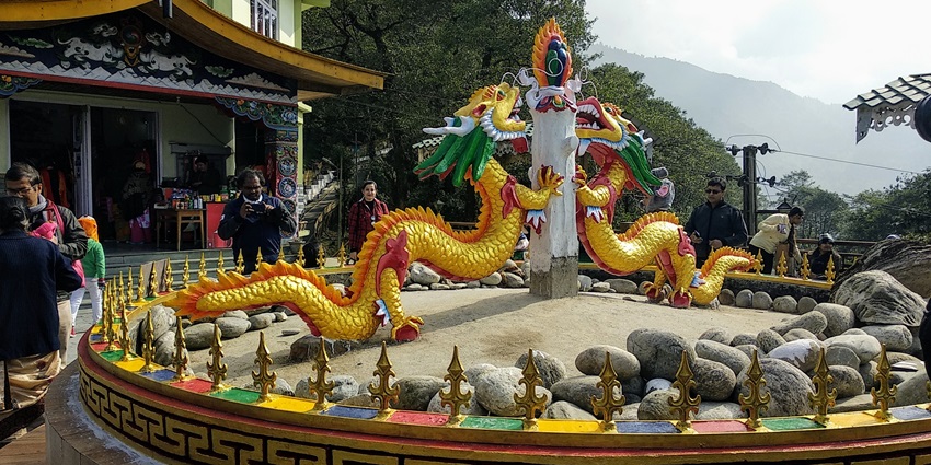 A picture of a majestic dragon statue in Sikkim with views of the mountains in background