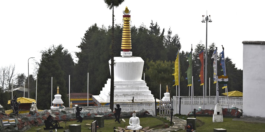 White walls of the war memorial with vibrant paintings all around it and a stupa in the middle