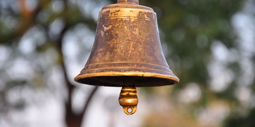 Ornate temple bell hanging from a wooden structure, ready to be rung - Jwalamukhi Mandir.