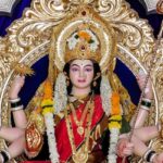 A glimpse of Durga statues set amidst a royal blue background on a silver throne.