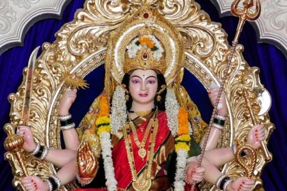 A glimpse of Durga statues set amidst a royal blue background on a silver throne.