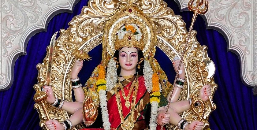 A glimpse of Durga statues set amidst a royal blue background on a silver throne.