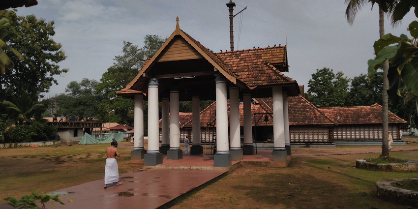 A picture of a priest bowing down in front of the Thrikkakara Temple during day time