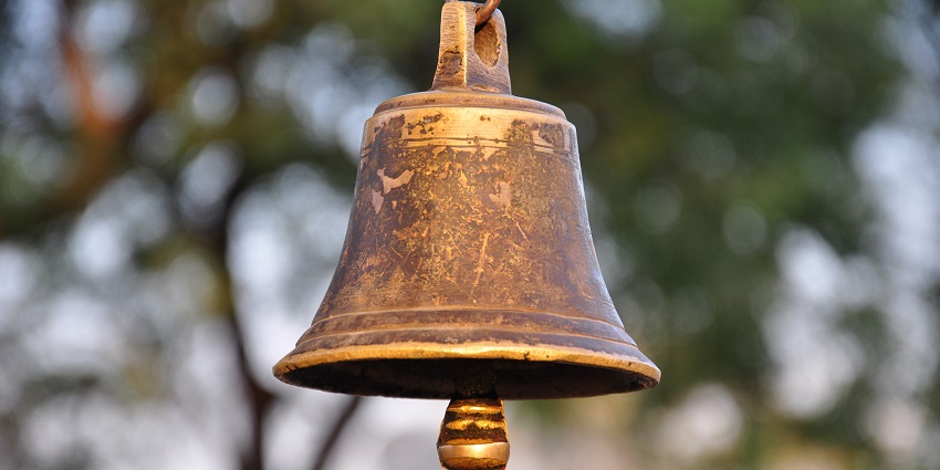 A serene temple bell hanging, ready to ring and create a peaceful atmosphere.