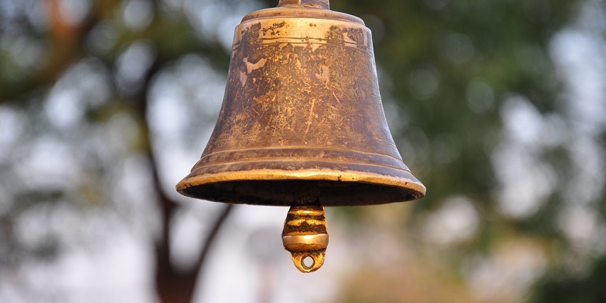 Temple bell hanging from a wooden structure, ready to be rung -Umananda Temple.
