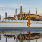 Monk walking on the side of a pond in a beautiful Buddhist temple in Bangkok, Thailand