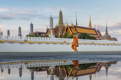 Monk walking on the side of a pond in a beautiful Buddhist temple in Bangkok, Thailand