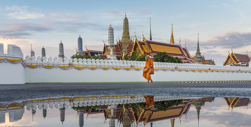 Monk walking on the side of a pond in a beautiful Buddhist temple in Bangkok, Thailand