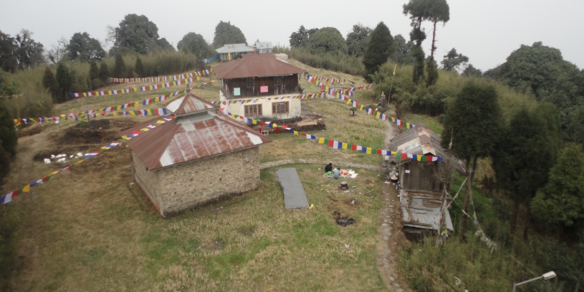 An aerial picture of a hilltop with hut-like accommodations and abundance of trees nearby