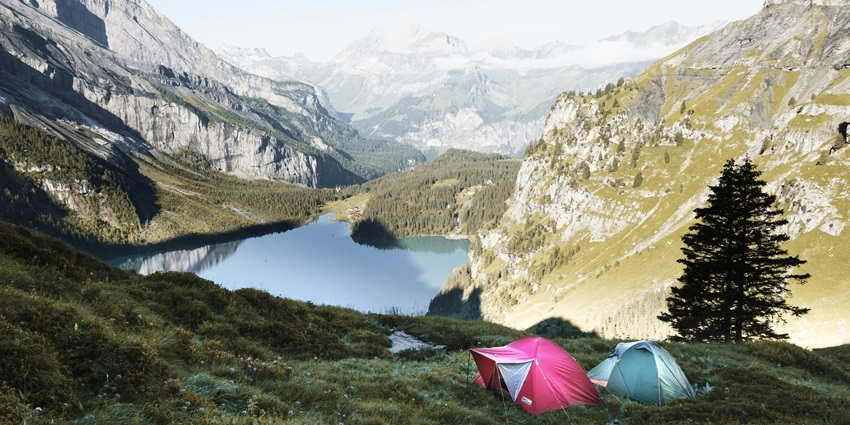 View of red and gray tents in grass covered mountain - explore Golden Meadows Camping Resort