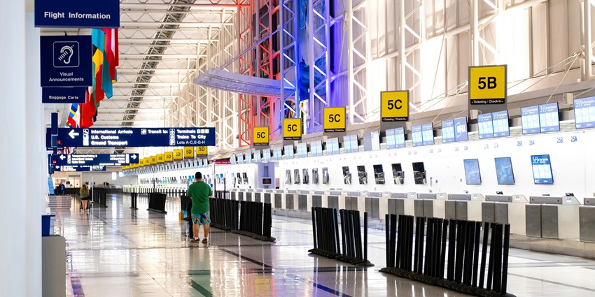 A guy is walking down the lane towards his terminal in the airport to catch a flight