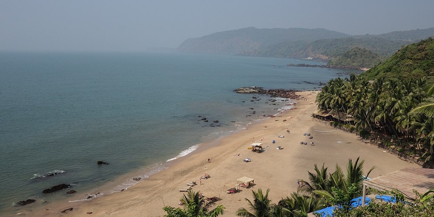 Secluded golden Beach similar to Thaikadappuram, with resort roofs framed by hills
