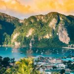 An aerial view of shimmering waters of Phi Phi Islands surrounded by green peaks.