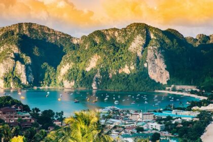 An aerial view of shimmering waters of Phi Phi Islands surrounded by green peaks.