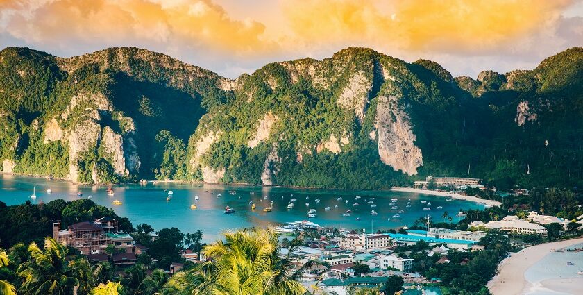 An aerial view of shimmering waters of Phi Phi Islands surrounded by green peaks.