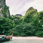 Boats decked on the seashore of the region surrounded by lush greenery and azure waters.