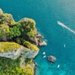 Miltiadis Fragkidis / Unsplash Alt Text: A view of turquoise-blue waters of Phi Phi Islands meeting the lush green surroundings.