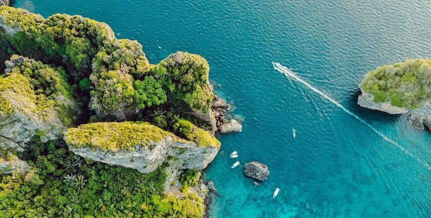 Miltiadis Fragkidis / Unsplash Alt Text: A view of turquoise-blue waters of Phi Phi Islands meeting the lush green surroundings.