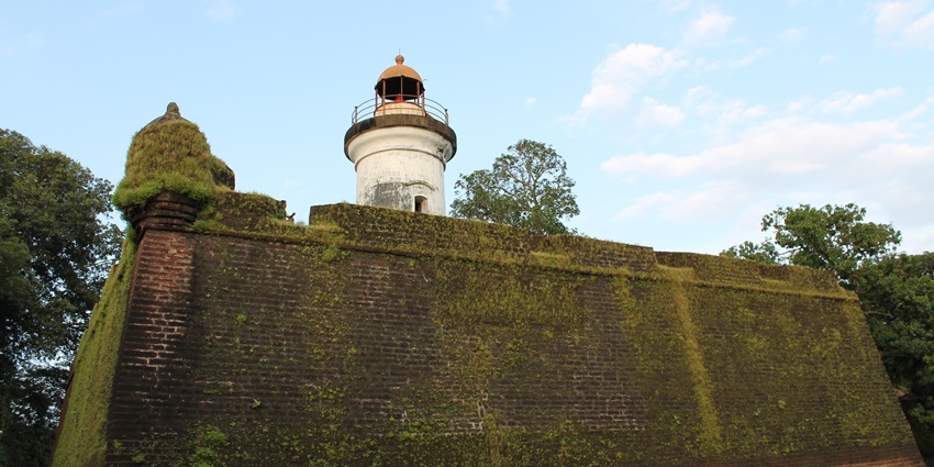 Close-up view of the moss-covered walls of Thalassery Fort, with the blue sky in background.