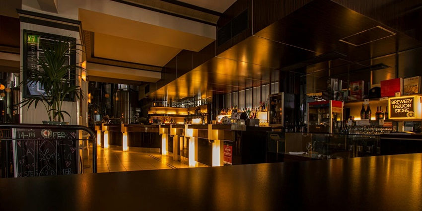 Empty bar filled with colorful lights and stylish decor, ready for evening patrons.