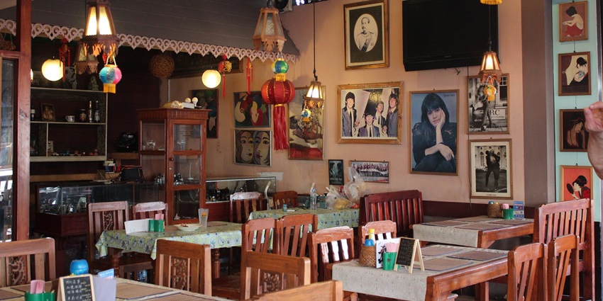 A picture of a nice cafe restaurant with wall paintings and a beautiful ambience having a multiple table arrangement