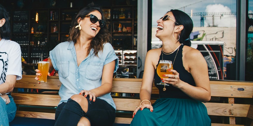 Women enjoying drinks while sitting on a bench