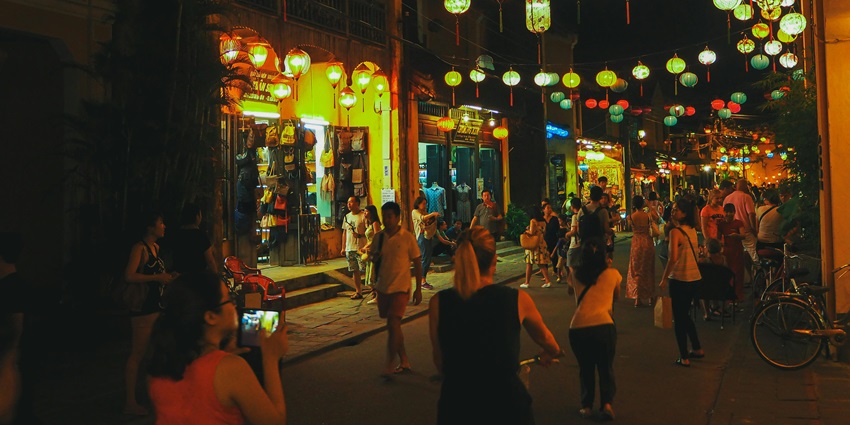Anonymous people relaxing and chatting on a street in a town district at night.