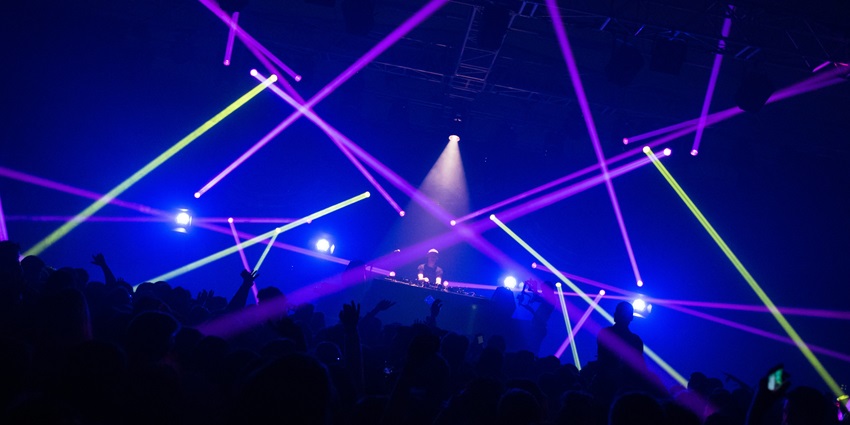 An inside view of a club adorned with neon lights and people grooving to the beats.
