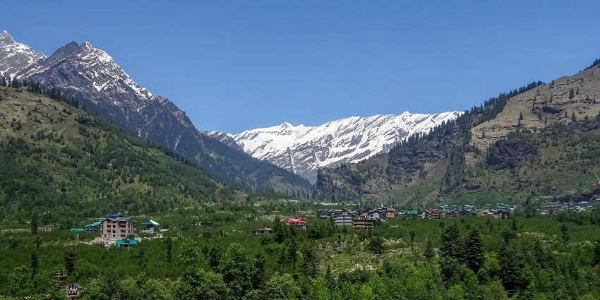 Beautiful Kullu Valley landscape featuring green hills and a bright blue sky in India.