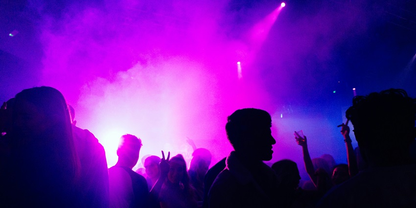 A view of the Lighthouse Sky Bar featuring people dancing on the floor with neon lights.