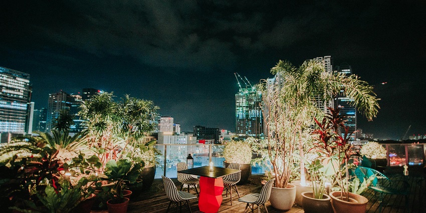 Evening terrace with potted plants and modern houses in the background.