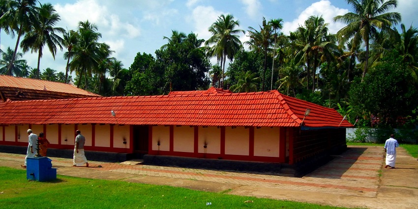 A picture of a Thrissur temple with a garden area surrounding the main temple