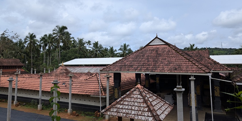 A frontal view of the entrance of a traditional Hindu temple with a garden area