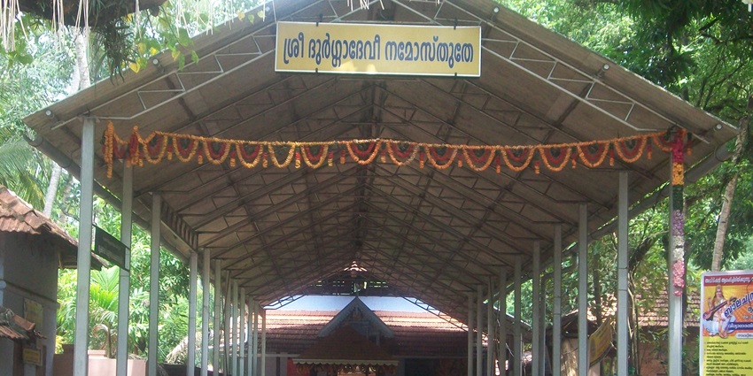 Covered walkway leading to a traditional temple entrance, with people gathered nearby