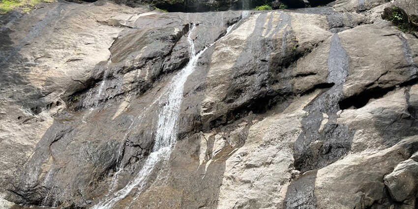 Appealing view of Thusharagiri Waterfalls falling over huge rocks encircled by greenery.