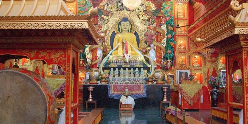 A picture of a praying region in a Buddha temple in Delhi with wall paintings and sculpture of Lord Buddha