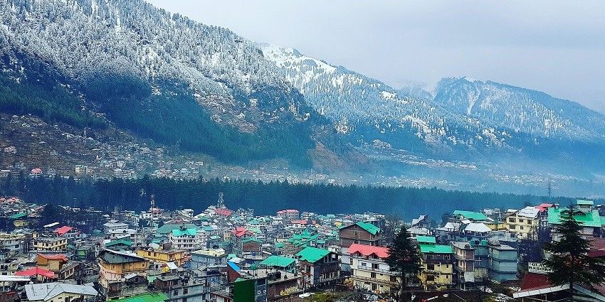 An aerial view of the city of Manali with scenic landscapes and green hills