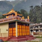 A picture of a Tibetan monastery in Manali with the beautiful green mountains in background