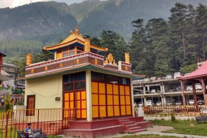 A picture of a Tibetan monastery in Manali with the beautiful green mountains in background