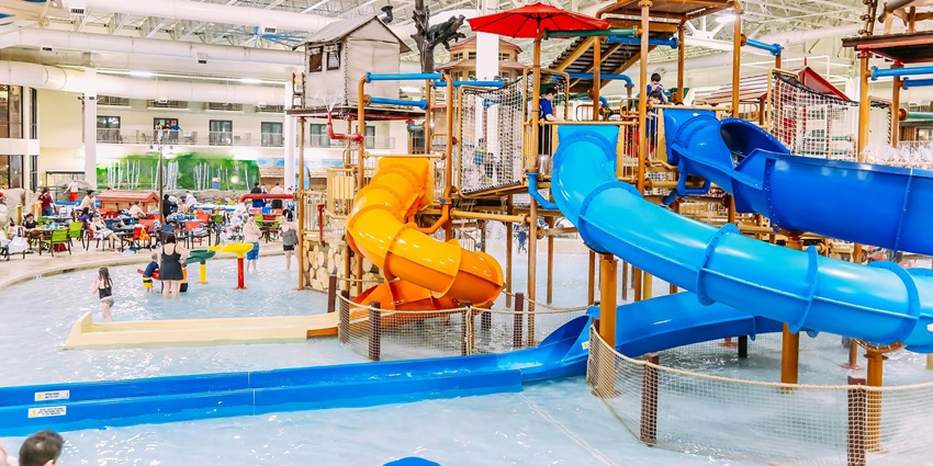 A mesmerising view of an indoor water park with a large blue and yellow slide in between.