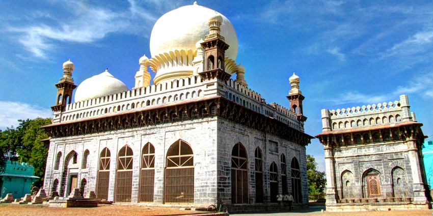 A picture of a marble building with a dome on top and a smaller complex behind it