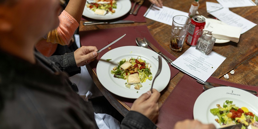 A picture of people sitting at a round-table and enjoying the food at a restaurant