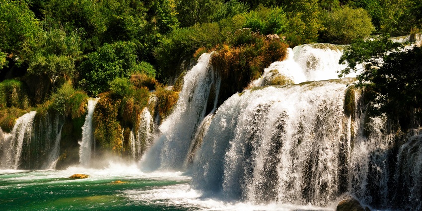 Triple Falls in Nagaland with three cascading down rocky cliffs into a lush, green valley.